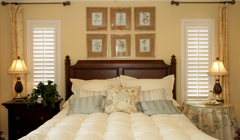 Tall plantation shutters framing bed in a bedroom in Southern California 